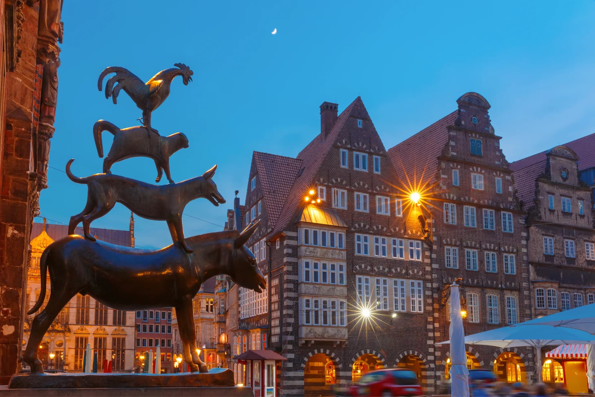 Bremer Stadtmusikanten vor Gebäuden am Marktplatz bei Dämmerung
